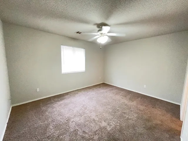 an empty room with a window and a fan