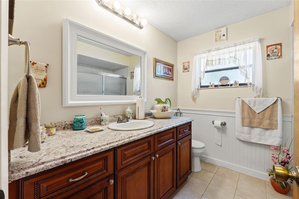 4151 Montano Avenue Spring Hill, FL 34609 - Photo 19 of 34 a bathroom with a granite countertop sink mirror and vanity