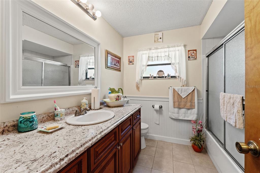 4151 Montano Avenue Spring Hill, FL 34609 - Photo 20 of 34 a spacious bathroom with a granite countertop sink a mirror and a bath tub