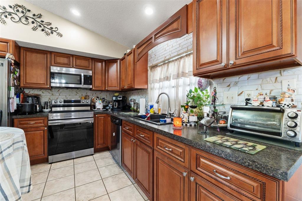 4151 Montano Avenue Spring Hill, FL 34609 - Photo 24 of 34 a kitchen with stainless steel appliances granite countertop a stove top oven a sink dishwasher and cabinets with wooden floor