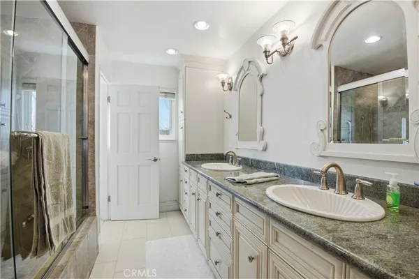 a bathroom with a granite countertop sink a large mirror and a shower
