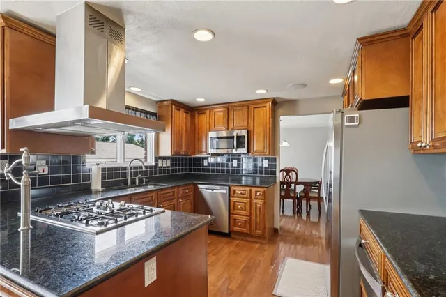 a kitchen with stainless steel appliances granite countertop a stove a sink and a dining table