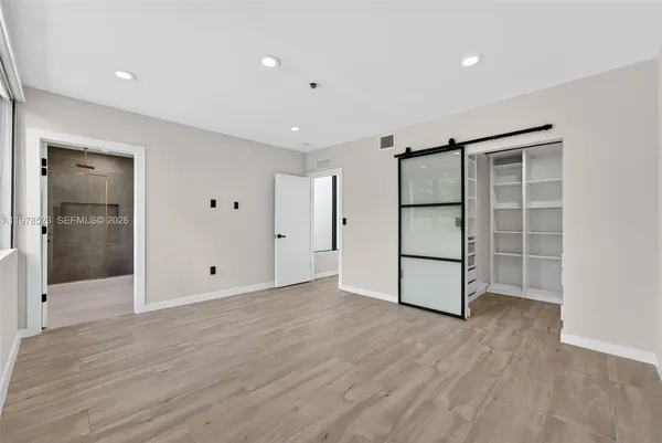 a view of an empty room with wooden floor and closet