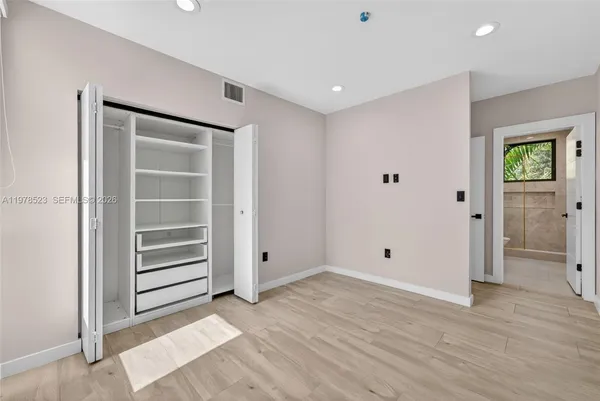 a view of an empty room with closet and a window