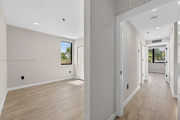a view of a hallway with wooden floor and a bathroom