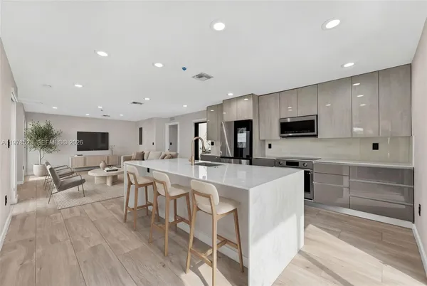 a large white kitchen with lots of counter space a sink appliances and cabinets