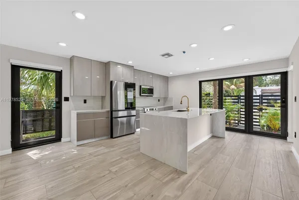a large white kitchen with large windows and refrigerator