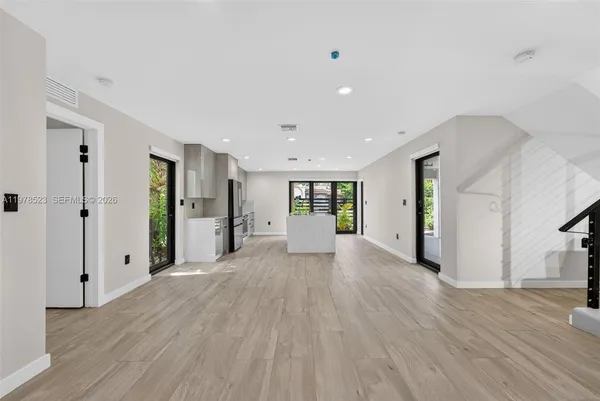 a view of a big room with wooden floor and windows
