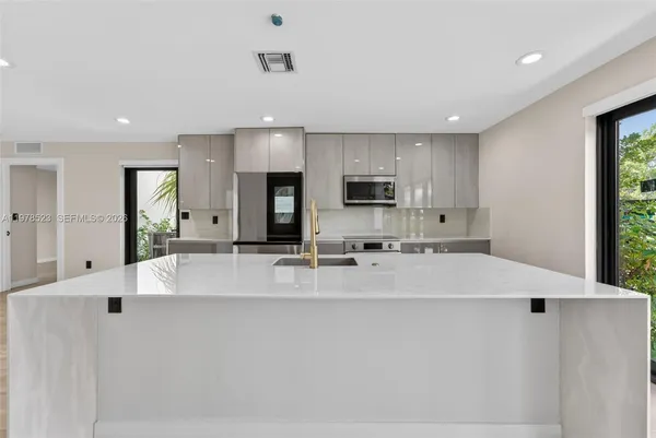 a large white kitchen with kitchen island a stove a sink a refrigerator and white cabinets with wooden floor