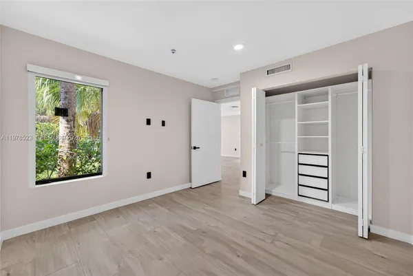 a view of an empty room with wooden floor and windows