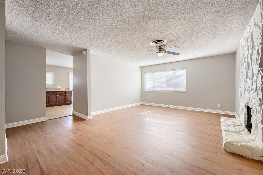 6321 Portola Road Las Vegas, NV 89108 - Photo 7 of 29 A versatile living area with wood flooring and a distinctive stone fireplace.