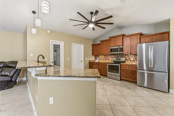a kitchen with stainless steel appliances granite countertop a sink a stove a refrigerator a washer dryer and white cabinets