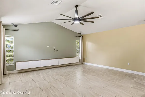 a view of an empty room with wooden floor and a ceiling fan