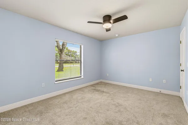 an empty room with windows and fan view