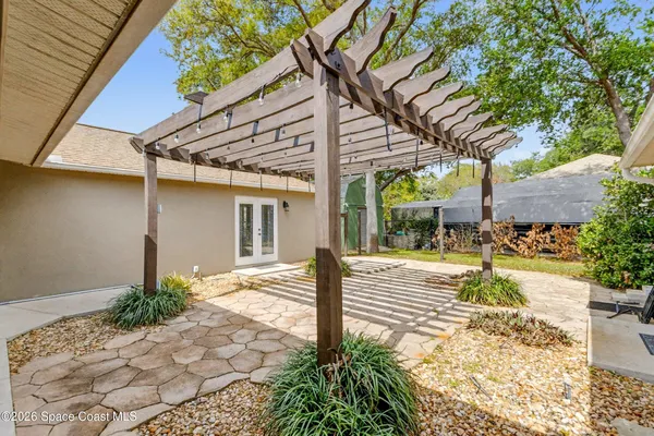 a view of a patio with table and chairs potted plants and large tree