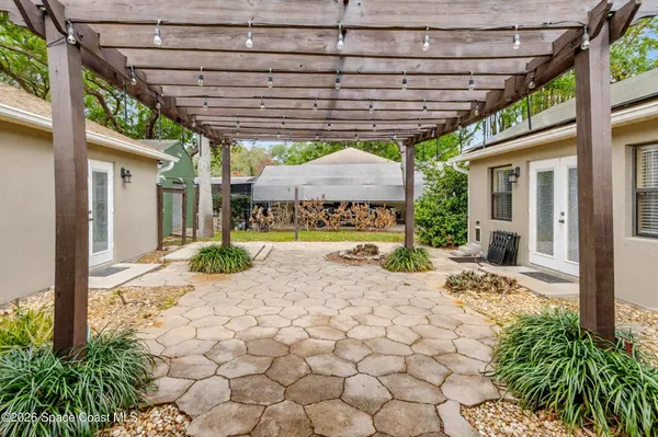 a patio with a table and chairs and potted plants