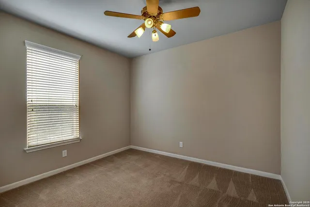 an empty room with a window and a fan