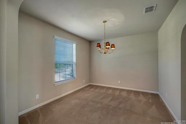 an empty room with windows and chandelier fan