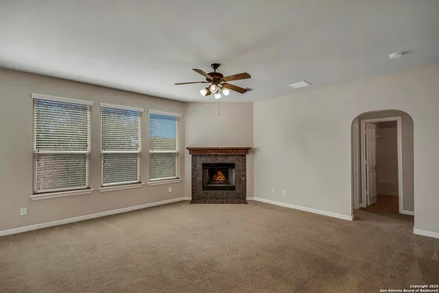 an empty room with fireplace fan and windows