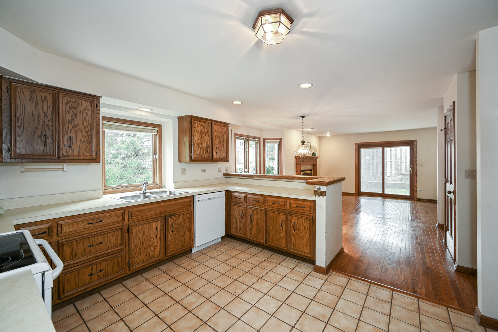 520 Renn Court Wheaton, IL 60187 - Photo 16 of 33 a large kitchen with white cabinets a sink dishwasher a dining table and chairs with wooden floor