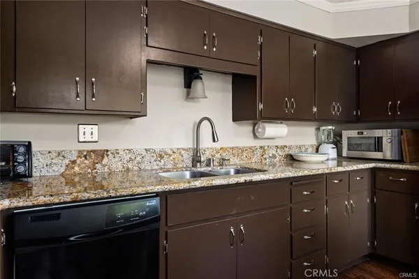 a kitchen with granite countertop a sink a stove and cabinets