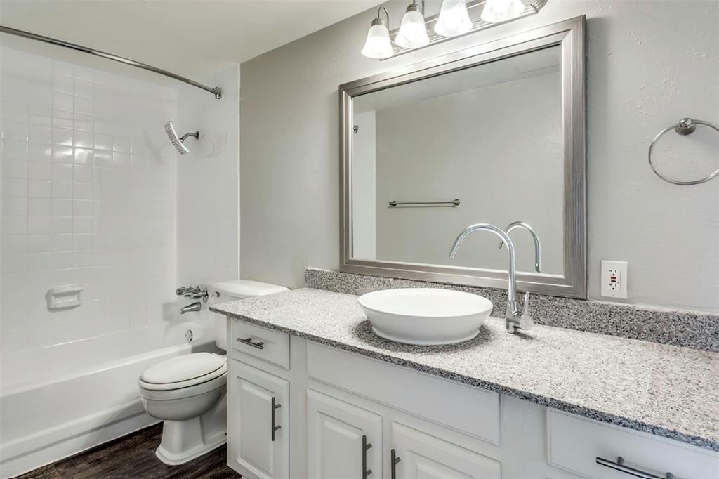 a bathroom with a granite countertop sink a toilet and a mirror
