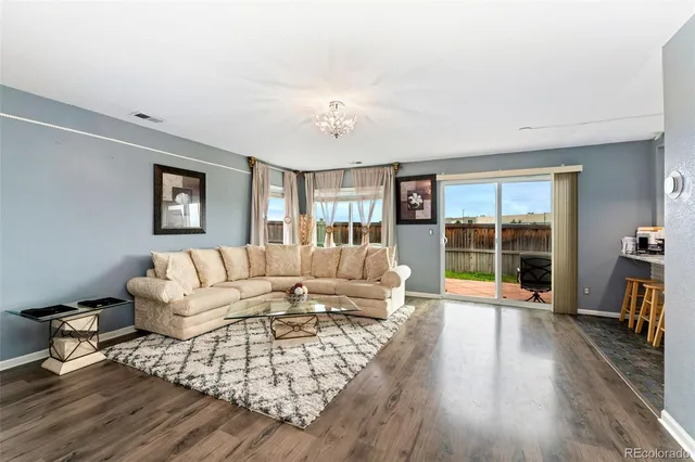 a living room with furniture large wooden floor and a large window