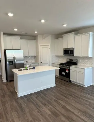 a large kitchen with cabinets wooden floor and stainless steel appliances