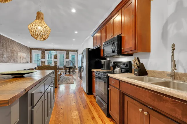 a kitchen with stainless steel appliances granite countertop a sink a stove and a wooden floors