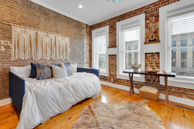 a spacious bedroom with a bed a couch and large windows