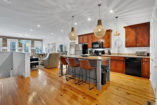 a kitchen with stainless steel appliances granite countertop a stove top oven a sink dishwasher a dining table and chairs with wooden floor