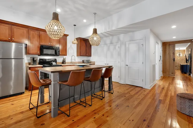 a kitchen with stainless steel appliances a dining table chairs stove and refrigerator