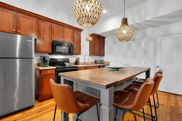 a kitchen with a refrigerator a stove a kitchen island a dining table and chairs with wooden floor