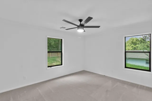 an empty room with a window and a ceiling fan