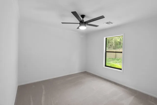 an empty room with windows and fan