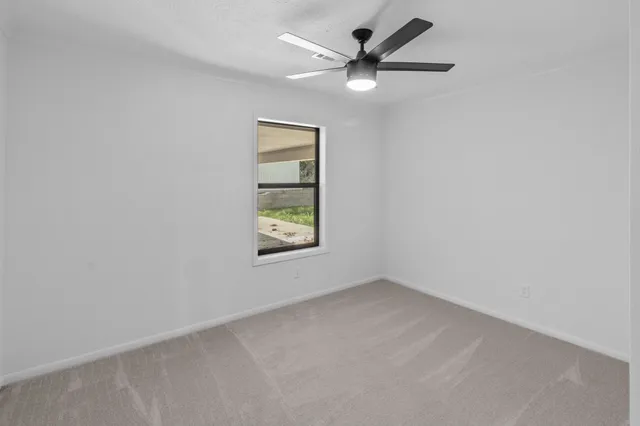 an empty room with a window and a fan