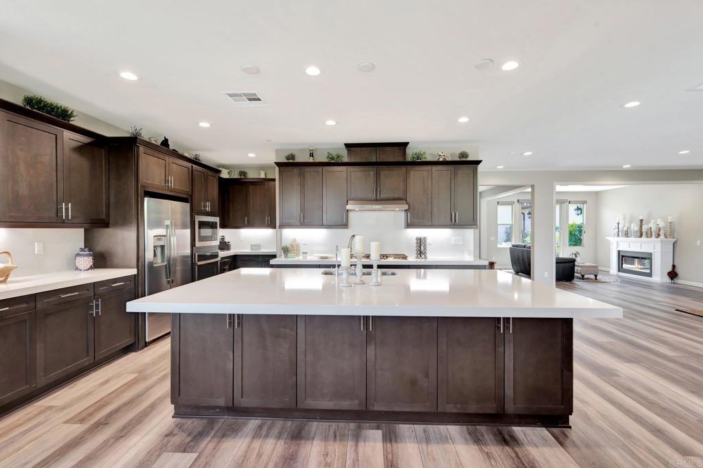 22005 Long Trot Drive Escondido, CA 92029 - Photo 4 of 51 a large kitchen with kitchen island a sink dishwasher a stove and a refrigerator with wooden floor