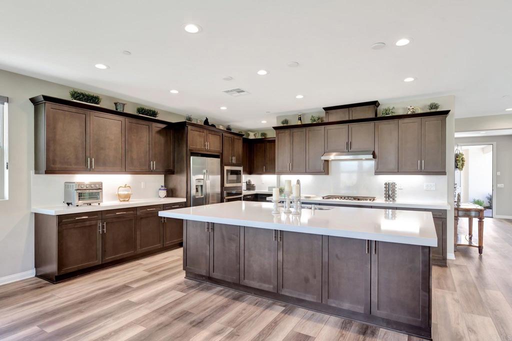 22005 Long Trot Drive Escondido, CA 92029 - Photo 5 of 51 a kitchen with kitchen island granite countertop a sink and wooden cabinets