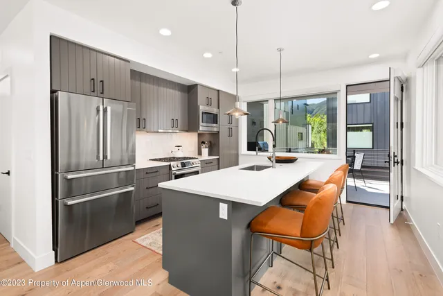 a kitchen with stainless steel appliances kitchen island granite countertop a refrigerator a oven a sink with a dining table and chairs