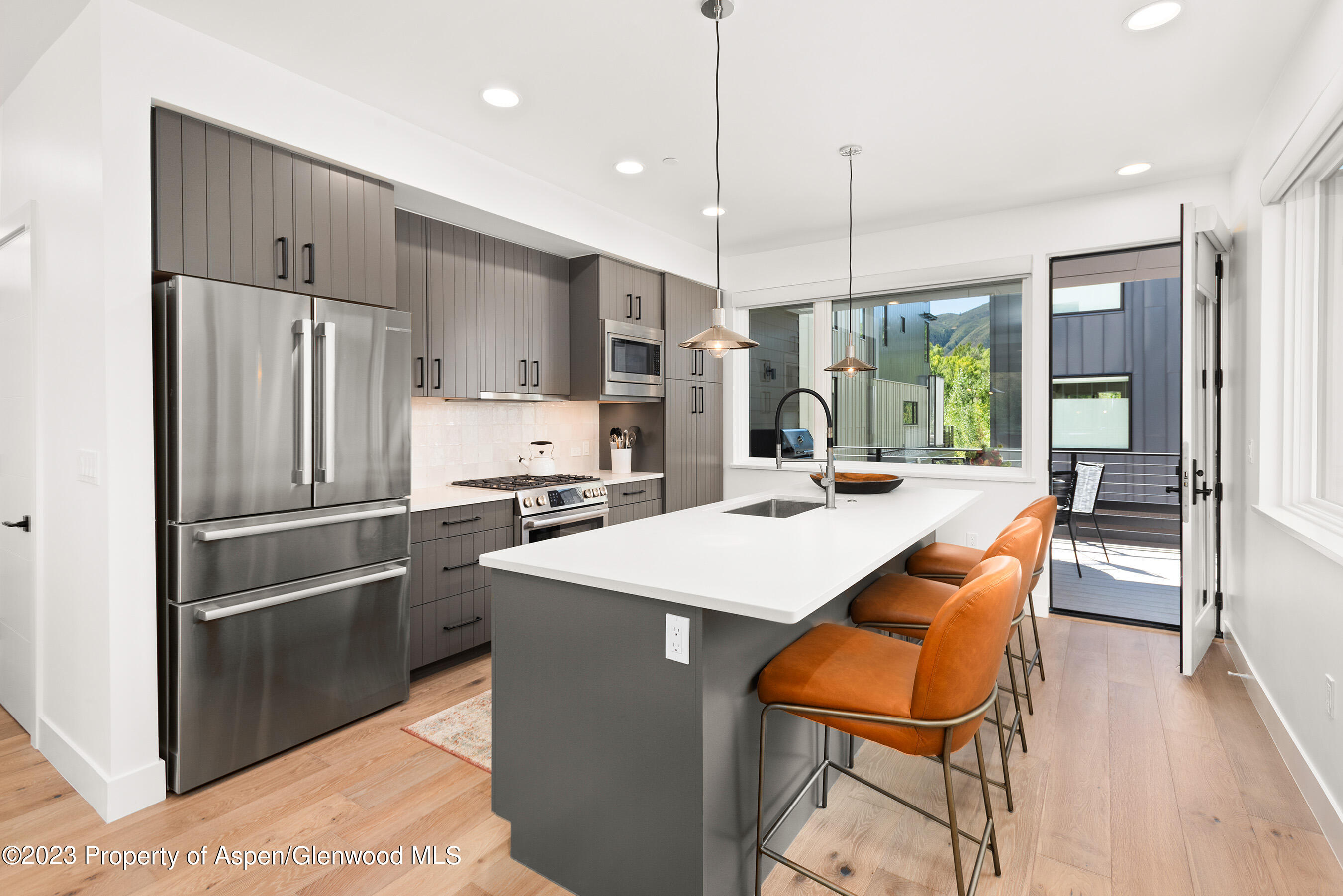 22842 Two Rivers Road, Unit 100 Basalt, CO 81621 - Photo 7 of 22 a kitchen with stainless steel appliances kitchen island granite countertop a refrigerator a oven a sink with a dining table and chairs