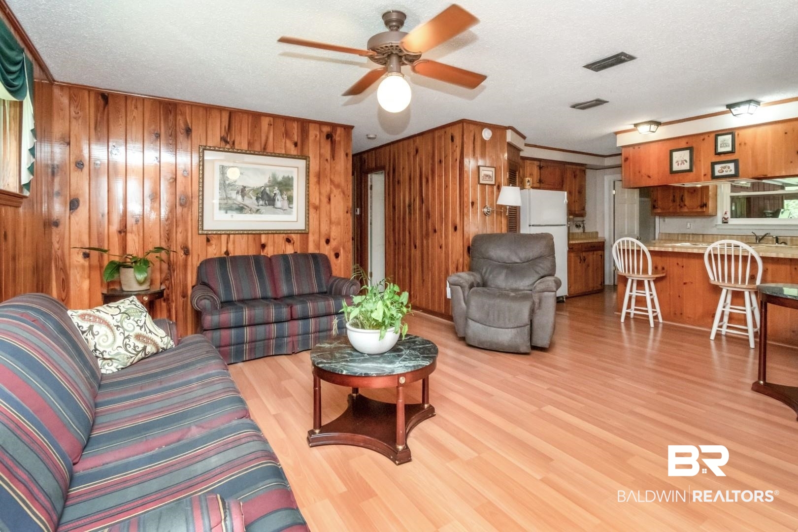 6300 Woodcrest Drive Mobile, AL 36608 - Photo 5 of 35 Living area with visible vents, a ceiling fan, a textured ceiling, wooden walls, and light wood-style flooring