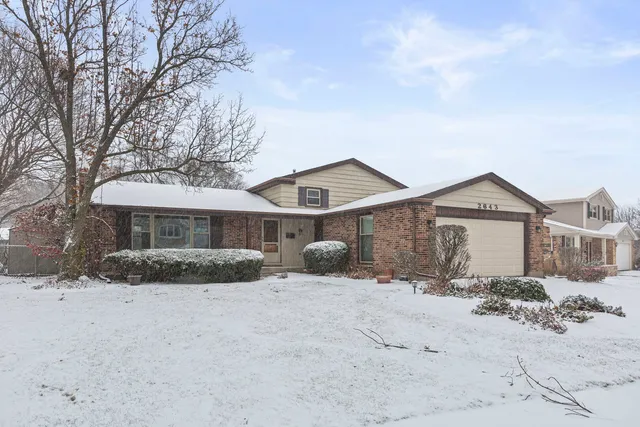 a front view of a house with a yard covered in snow