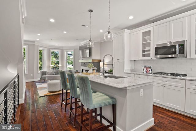 a kitchen with stainless steel appliances granite countertop a stove top oven a sink a dining table and chairs with wooden floor