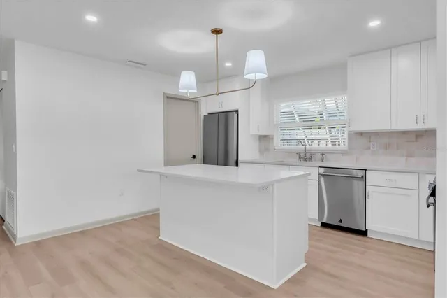 a kitchen with stainless steel appliances granite countertop a sink a stove a refrigerator and island with wooden floor