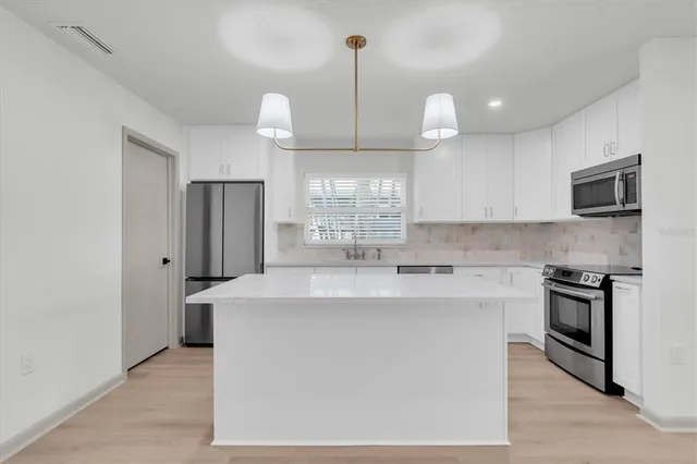 a kitchen with stainless steel appliances granite countertop a sink dishwasher stove and microwave with wooden floor