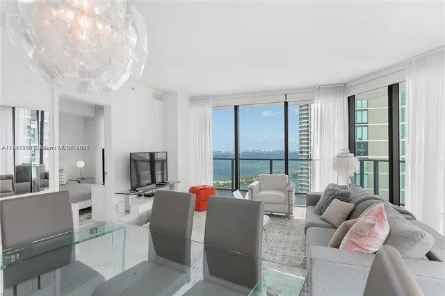 a living room with furniture a flat screen tv and a floor to ceiling window
