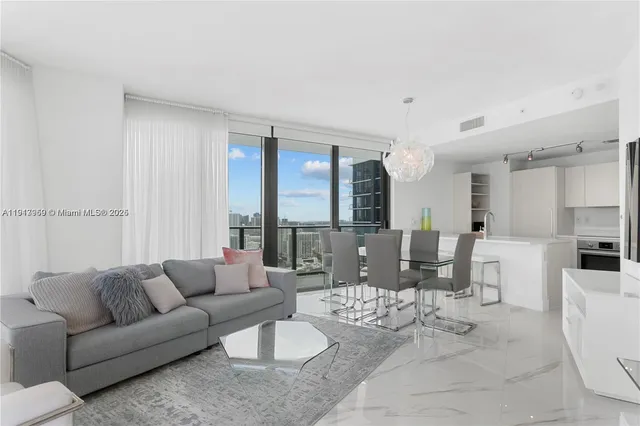 a living room with furniture kitchen view and a large window