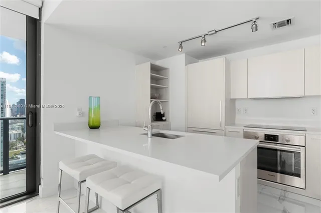 a kitchen with stainless steel appliances a sink a stove and a refrigerator with wooden floor