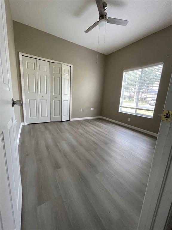 4939 Woodmere Road Land O Lakes, FL 34639 - Photo 17 of 43 an empty room with wooden floor chandelier fan and windows
