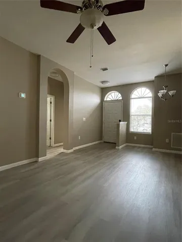 an empty room with wooden floor cabinet and windows